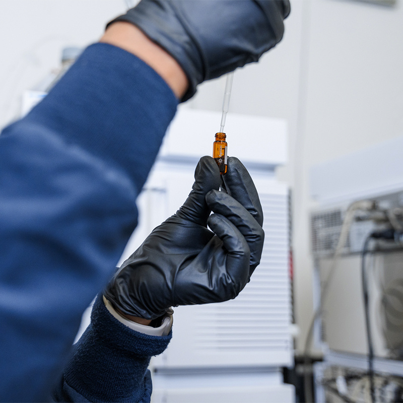 Employee extracting material from a vial. 