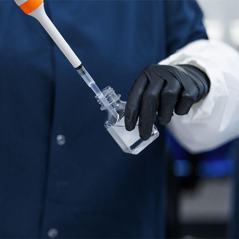 American Injectables employee extracting material from vial in full PPE. 