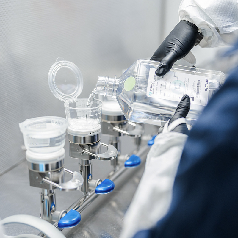 American Injectables employee mixing materials in full PPE. 