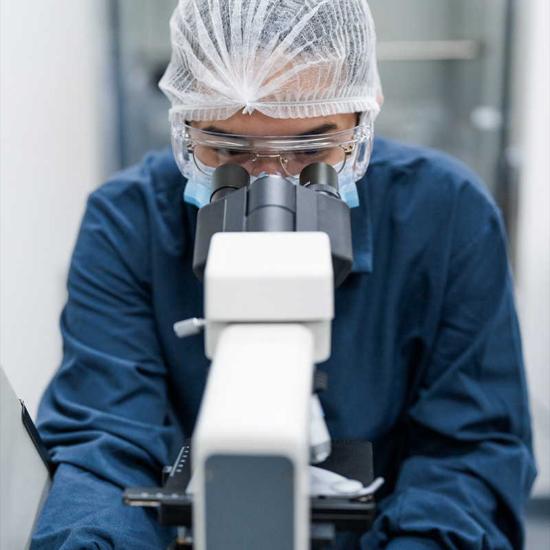 Employee looking into a microscope. 